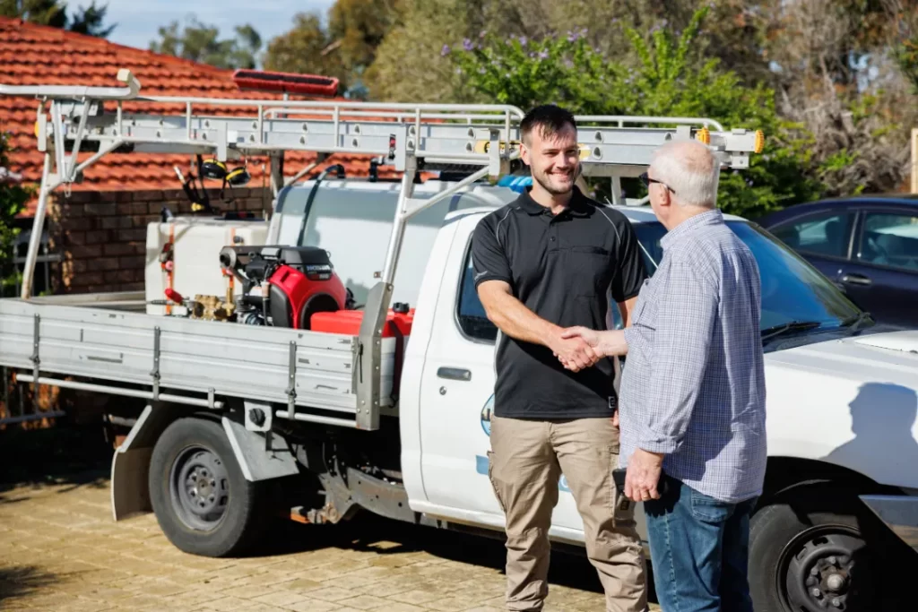 Shaking hands with a happy customers beside the work vehicle